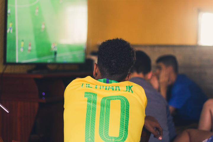 homem assistindo futebol camisa brasil