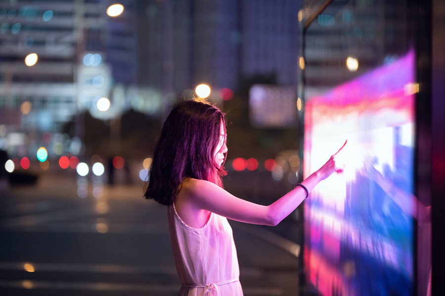 mujer tocando pantalla iluminada
