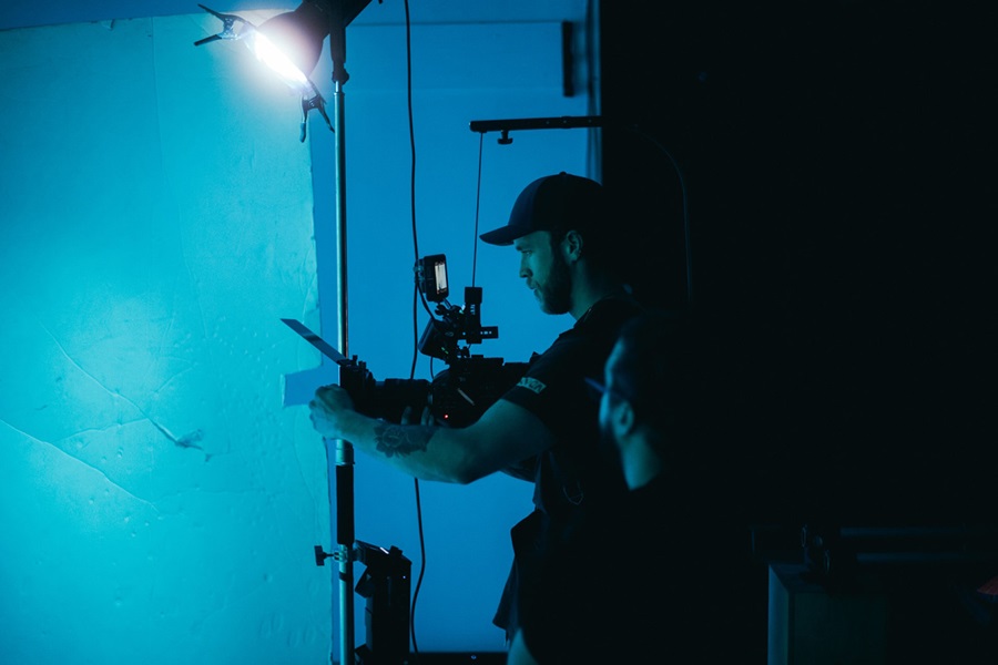 Man holding video camera in blue lit scene